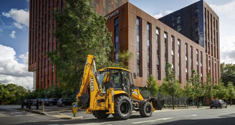 all-new JCB 3CX in front of city building, driving on the road