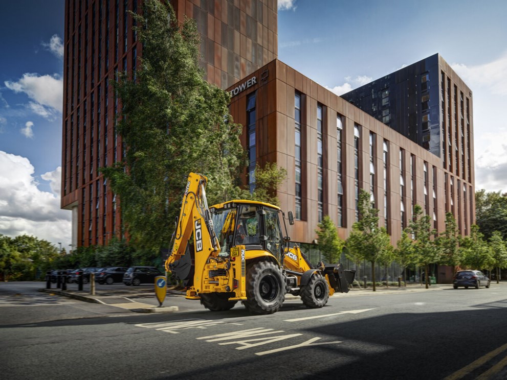 all-new JCB 3CX in front of city building, driving on the road